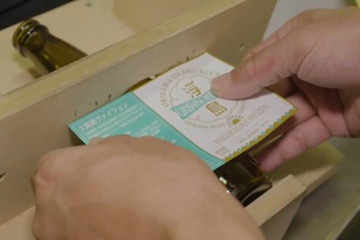 手作業で行われるボトルのラベル貼り