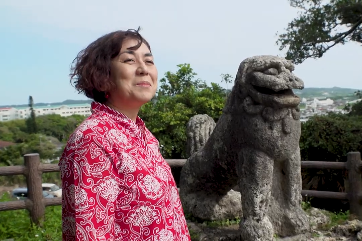 沖縄県内で最大・最古といわれる石獅子(シーサー)と並ぶ女性