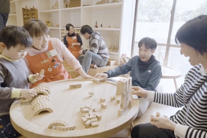 赤いエプロンをつけたスタッフたちと遊ぶ人々