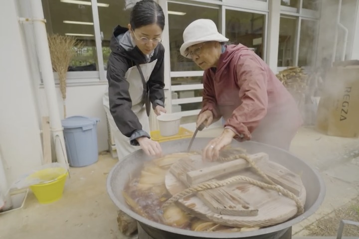 苧炊き作業。大鍋に木灰汁を沸騰させ、縄を底に敷いて、その上に束ねた原皮を重ねて煮ます